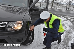 Policjant drogówki sprawdza stan techniczny pojazdu.